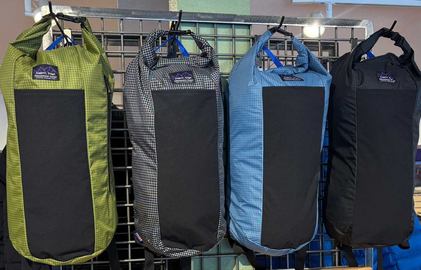 Four Jam Packs hanging on slat wall order left to right in green, grey, blue, and black