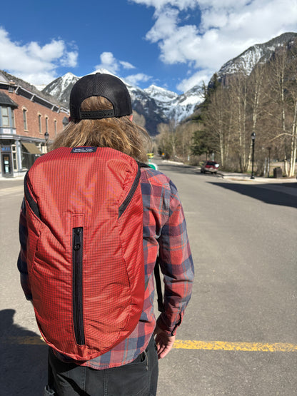 Person wearing a red Jagged Edge Ajax Pack with a scenic mountain background