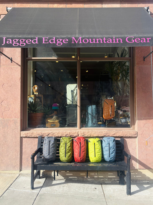 Colorful backpacks on a bench outside Jagged Edge Mountain Gear store.