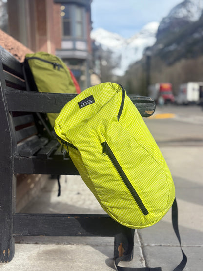 Lime green backpack on a bench with a mountainous background