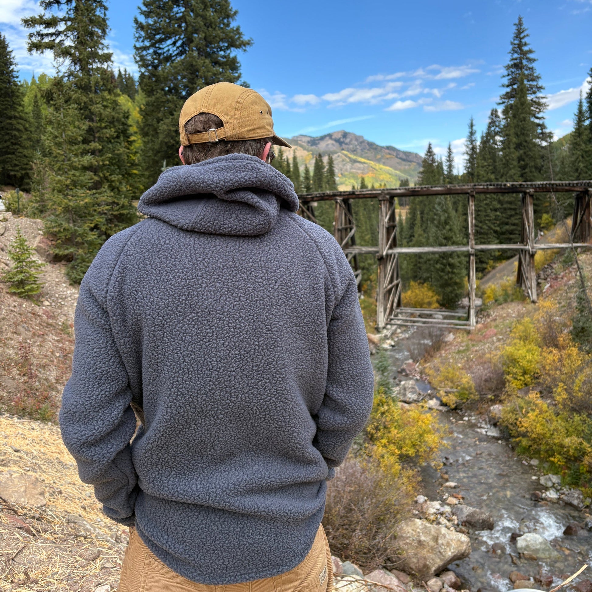 A person standing in front of the Telluride Trestle wearing the Jagged Edge High Pile Fleece Hoodie