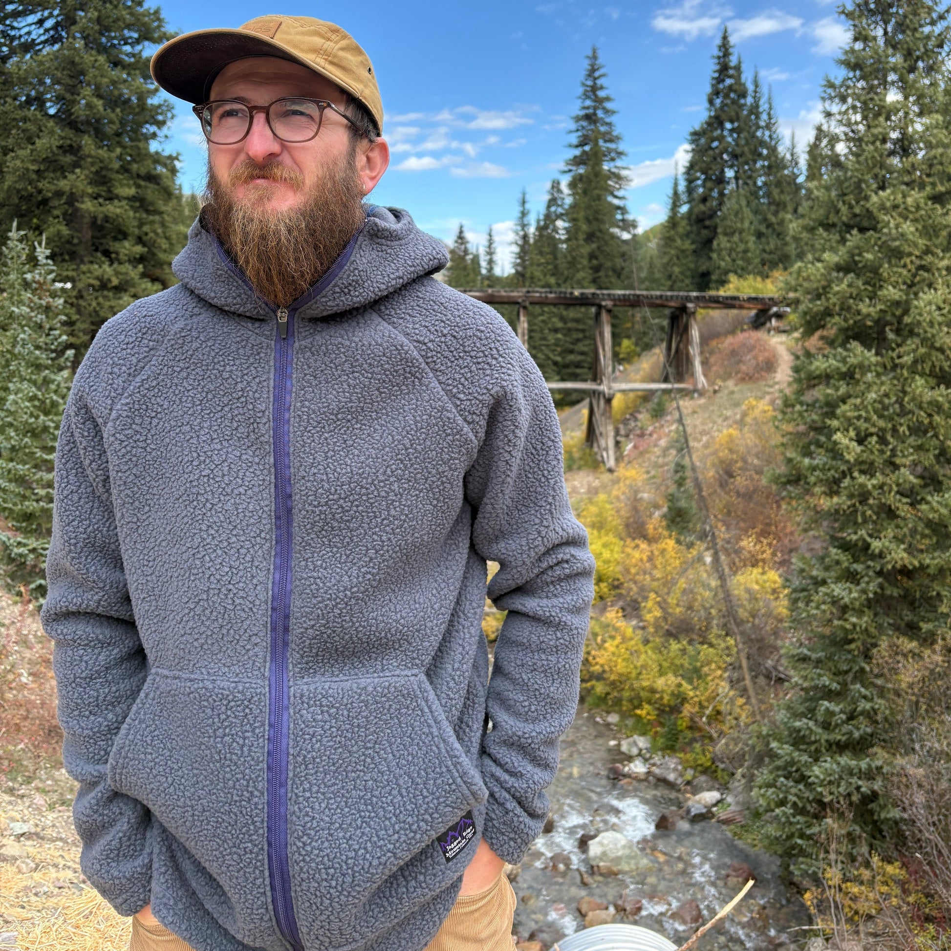 A person standing in front of the Telluride Trestle wearing the Jagged Edge High Pile Fleece Hoodie